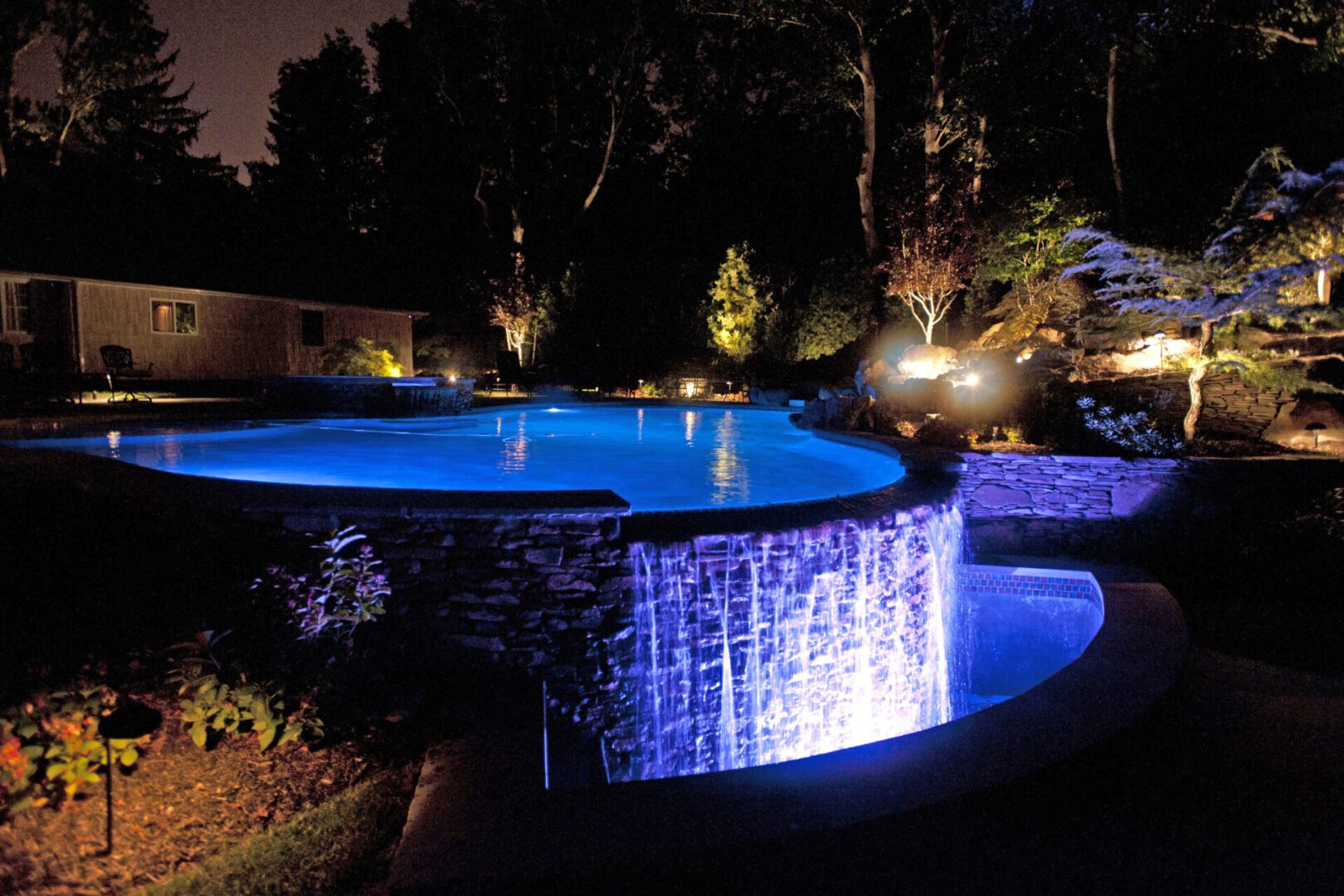 Tranquil lit pool and waterfall scene